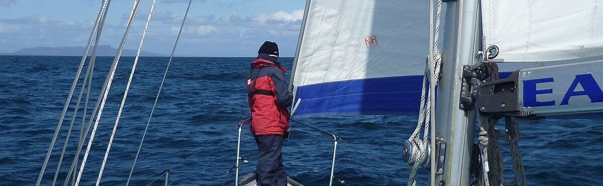 A crew member standing at the bow of sail training yacht East End Endeavour as the boat sails towards the Hebrides